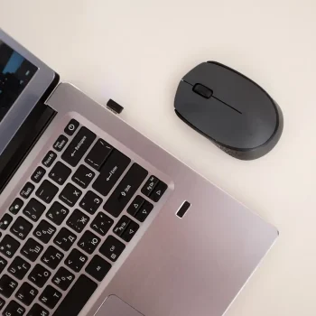 Laptop and mouse with an orange overlay, promoting contact for multilingual transcription services.